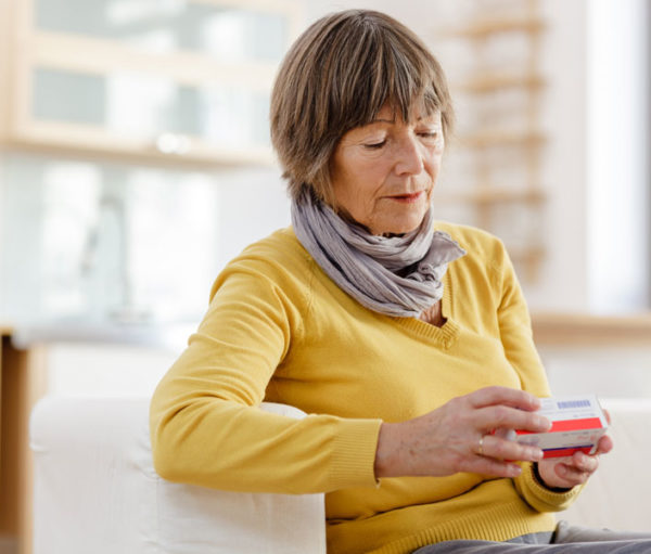 Woman reading label on pill bottle.