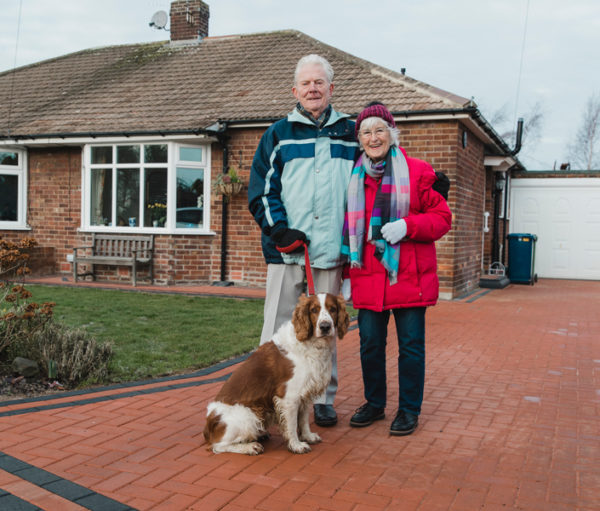 Senior couple with dog in front of house