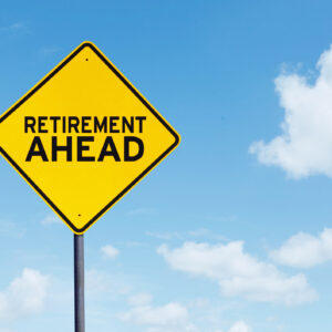 Picture of yellow highway sign with text of retirement ahead under blue sky